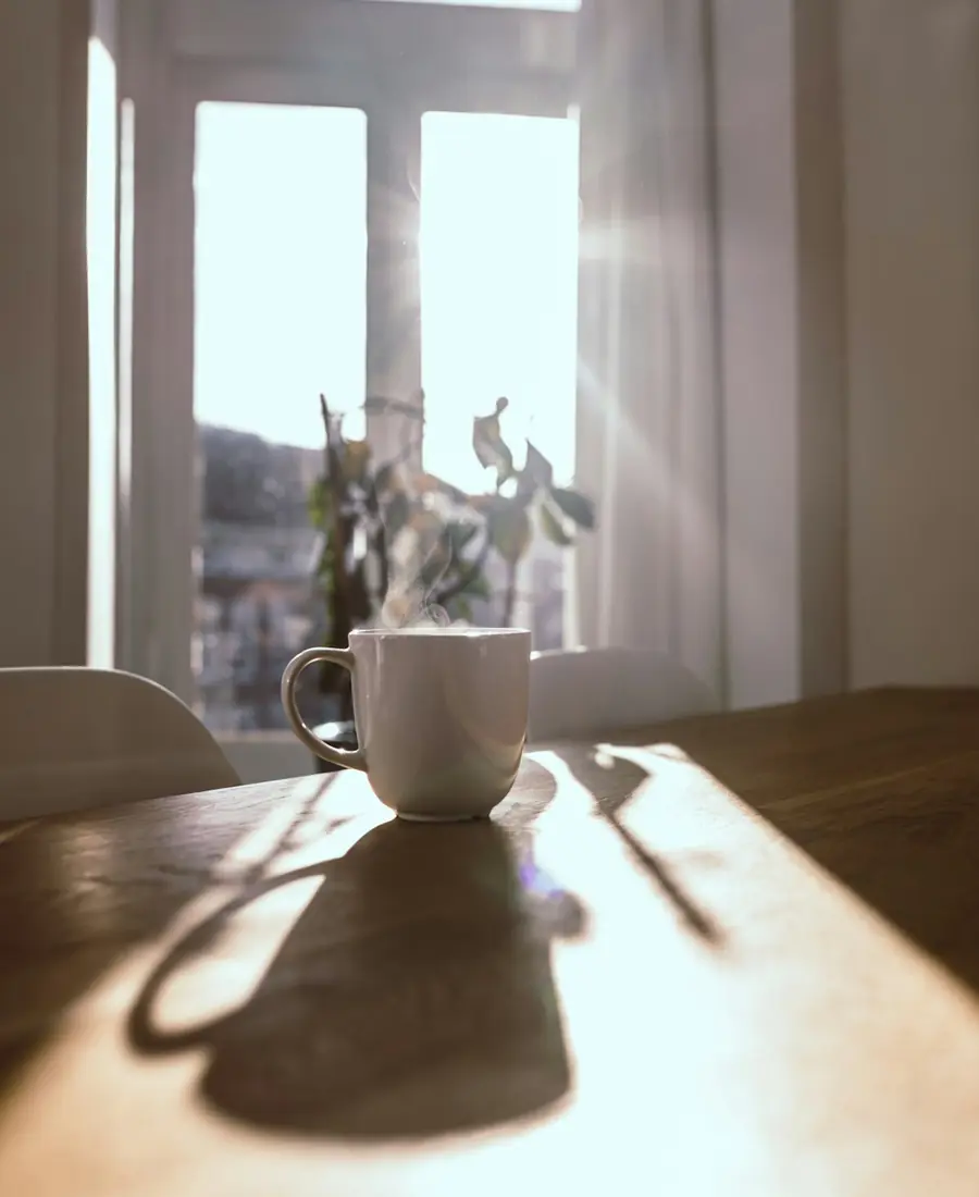 A cup of coffee on a sunlit table in the morning